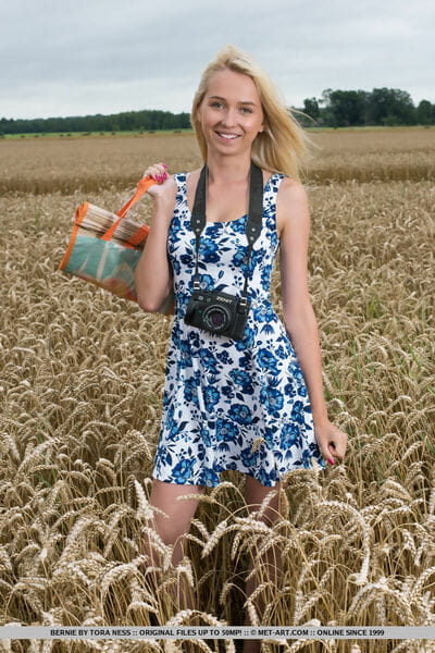 Teen blond Bernie removes her short clothing to pose nude in the wheat field