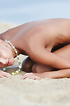Limber golden-haired Afina meditating undressed and expanding on the beach