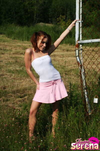 tiener redhead mooi Serena valt een petticoat over haar riem kleding afval in een veld