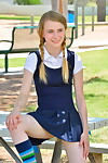 Miniature schoolgirl Sharlotte in uniform changes direction for a without clothes upskirt outside