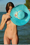 Youthful doll Nicole K modeling in nature\'s garb on beach wearing a sun hat