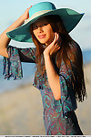 Youthful doll Nicole K modeling in nature\'s garb on beach wearing a sun hat